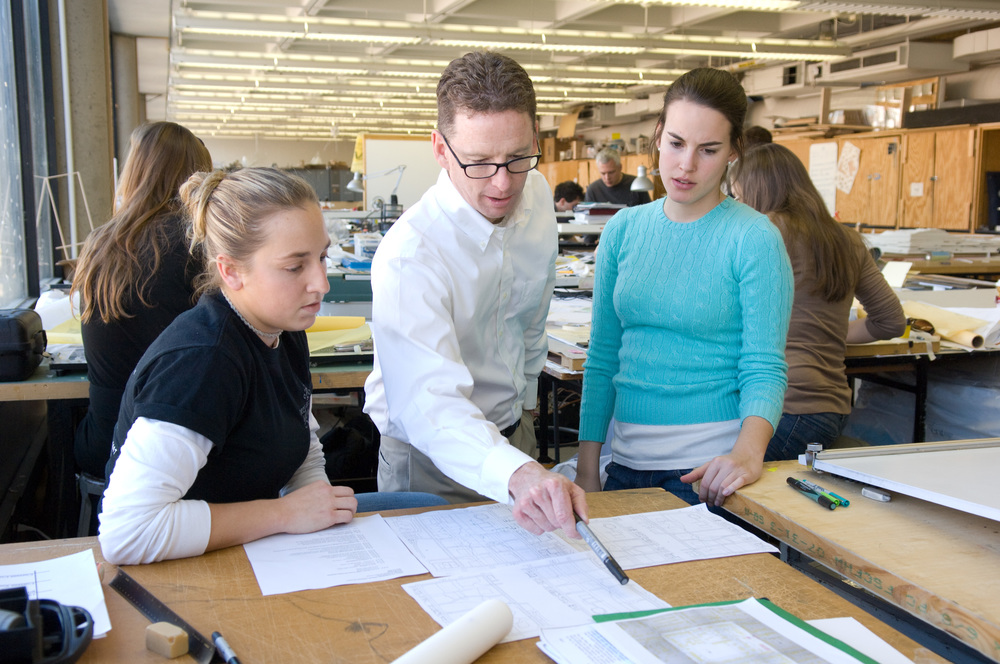 Professors and teaching assistants are pictured with students in classroom settings. David Green (center), professor, in a studio classroom in the West Architecture building.